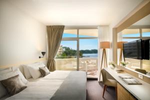 察夫塔特Remisens Hotel Albatros-All inclusive的酒店客房配有一张床、一张书桌和一台电视。