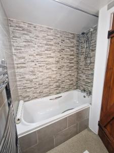 霍普Ash Cottage的砖墙浴室内的白色浴缸