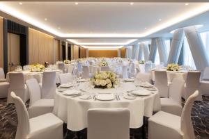 地拉那Tirana Marriott Hotel的一个带白色桌子和白色椅子的宴会厅和一间带窗户的房间