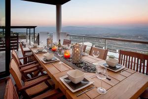 帕福斯Villa Arcadia, Kallepia的阳台上配有带盘子和玻璃杯的木桌