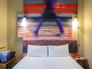 米兰宜必思米兰中心酒店的一张床上的房间,上面画着一个人走下楼梯的画