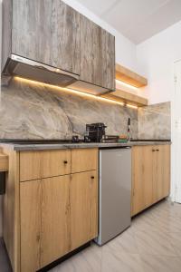 法里拉基Jimmy’s Garden的厨房配有木制橱柜和白色冰箱。