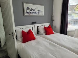 滨海绍森德Edelweiss Guest House的卧室内配有两张带红色枕头的白色床。
