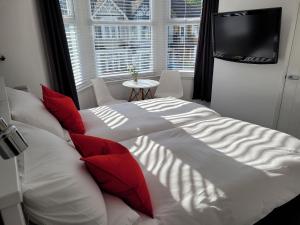 滨海绍森德Edelweiss Guest House的卧室内的一张带红色枕头的大型白色床