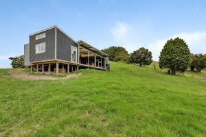 凯里凯里Waimate Farmstay - Kerikeri Holiday Home的绿草丛生的山丘上的房子