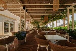 马卡尔斯卡奥斯亚法酒店的一间设有桌椅的餐厅,种植了植物