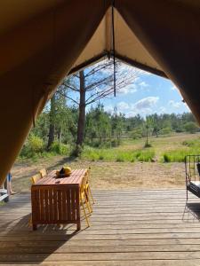 卡尔康Camping la Kahute, tente lodge au coeur de la forêt的木制甲板配有木桌和椅子