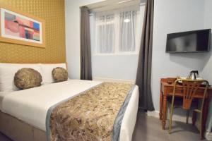 伦敦彭布里奇皇宫酒店的一间卧室配有一张床、一张书桌和一台电视