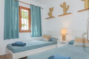 卡拉达沃Villa Dora的配有蓝色窗帘和窗户的客房内的两张床