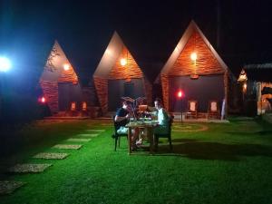 达瓦拉维Atha Safari Resort & Riverside Camping的两人晚上坐在房子前面的桌子上