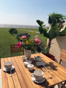 沙特拉永普拉日Studio-terrasse 3* bord de mer Châtelaillon plage的一张木桌,上面有杯子和碟子,花