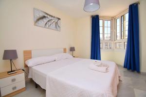 阿尔梅利马Expoholidays - Apartamentos Puerto Almerimar的卧室配有白色的床和蓝色窗帘