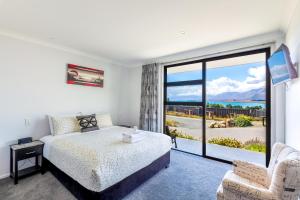 特卡波湖Roto View - Beautiful views of Lake Tekapo的一间卧室设有一张床和一个大窗户