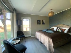 HelenaveenLandgoed Julianahoeve的卧室配有床、椅子和窗户。