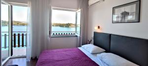 LukaPansion Alen - Dugi otok的一间卧室配有一张带紫色床罩的床和两个窗户。