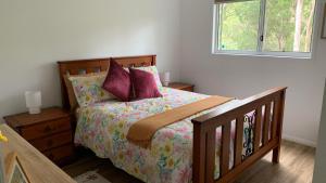 卡伦德拉Bush Beach Retreat的一间卧室配有一张带紫色枕头的床和窗户。