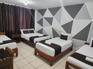 皮乌拉Hotel Villa del Sol的一间设有三张床的客房和一个带三角形的墙壁