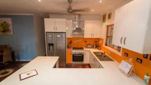 阿卡狄亚Tamarinds Beach House的厨房配有橙色和白色的橱柜和冰箱。