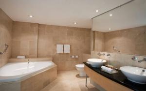 悉尼Holiday Inn Sydney Potts Point的一间带两个盥洗盆、浴缸和卫生间的浴室