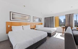 悉尼Holiday Inn Sydney Potts Point的酒店客房,设有两张床和一张沙发