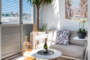 悉尼HolidayRento Boutique Terrace Apt in Bondi Beach的一间配有沙发和一张带葡萄酒瓶的桌子的房间