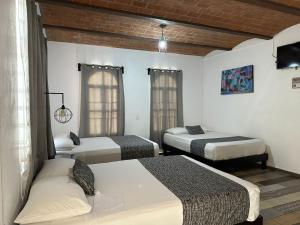 瓜纳华托Casa Malva Sweet Stay的客房设有三张床、一台电视和窗户。