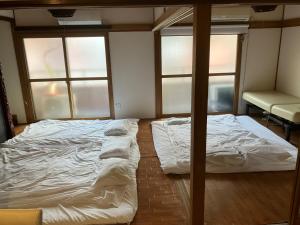 广岛Casa Viento Stay Inn的带2扇窗户的客房内的2张床