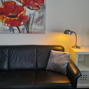皮尔默伦德B&B LandLust Guesthouse "Stay In Style " Amsterdam Area的客厅里一张黑色皮沙发,配有绘画作品