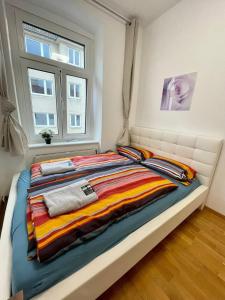 维也纳Deluxe Studio 3P TH的一张带彩色毯子和窗户的床