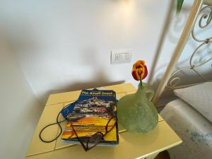 普莱伊亚诺Il Profumo dei Fiori的一张桌子,上面有花瓶,一本书和一朵花
