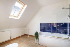 阿什伯恩Somersal Cottages的带浴缸的浴室和窗户。