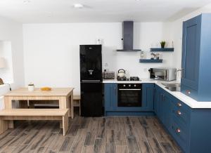 Shannon Castle Holiday Cottages Type B的厨房配有蓝色橱柜和木桌