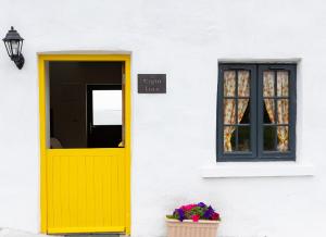 Shannon Castle Holiday Cottages Type C的白色建筑上的黄色门和窗户