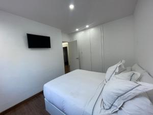 阿利坎特Chalet exclusivo bonalba的白色的卧室设有床铺和墙上的电视