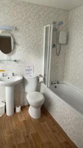 滨海韦斯顿皇家格罗夫纳酒店的浴室配有卫生间、盥洗盆和浴缸。