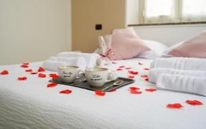 塞斯托卡伦德[Dalia Suite] Leonardo Academy, MXP & Lakes的床上的两杯咖啡,红色玫瑰花瓣