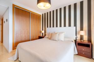 林孔-德拉维多利亚Ceres Malaga Apartamento de Lujo的卧室配有一张白色大床和条纹墙