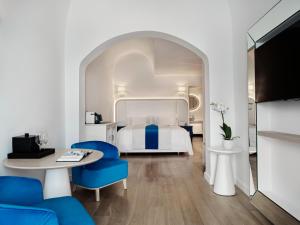 伊亚Katikies Santorini - The Leading Hotels Of The World的酒店客房带一张床、一张桌子和椅子