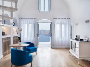 伊亚Katikies Santorini - The Leading Hotels Of The World的客厅配有桌子和蓝色椅子