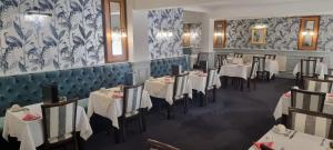 尚克林Ocean View Hotel的餐厅配有白色的桌椅,并拥有蓝色和白色的壁纸