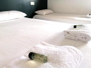 勒芒勒芒艾克洛酒店的白色床上放一瓶葡萄酒