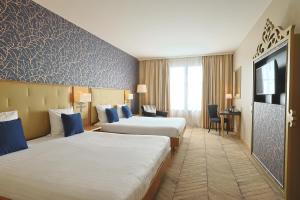 马尼库尔勒翁格尔Dream Castle Hotel Marne La Vallee的酒店客房设有两张床和电视。