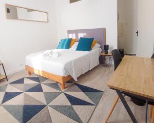 蒙吕松Artbleu -Tout Confort - Idéal Pros - Proche commerces的一间卧室配有一张带蓝色枕头的床和一张桌子