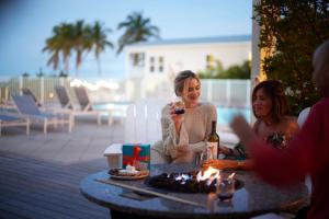 马拉松Courtyard by Marriott Faro Blanco Resort的两个女人坐在桌子边,喝了一瓶葡萄酒