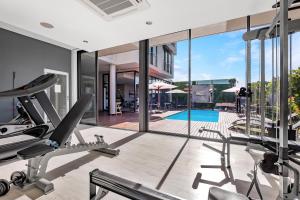 约翰内斯堡One Hyde Park Apartments Sandton的一个带跑步机的室内健身房和一个游泳池