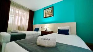 特鲁希略Hotel Country Trujillo的两张位于酒店客房的床,拥有蓝色的墙壁