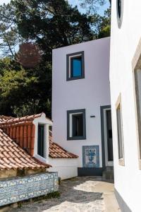 辛特拉Casinha - Lusitália Eden的白色的建筑,设有两扇窗户和一些屋顶