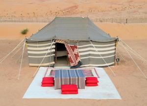 Ḩawīyah沙漠奇观营地酒店的沙漠中带红色椅子的帐篷