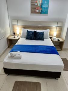 圣玛尔塔Hotel Boutique Deluxe的一间卧室配有一张大床,提供蓝色的床单和枕头