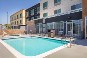 弗雷斯诺Fairfield Inn & Suites by Marriott Fresno North/Shaw Avenue的一座带椅子的游泳池以及一座建筑